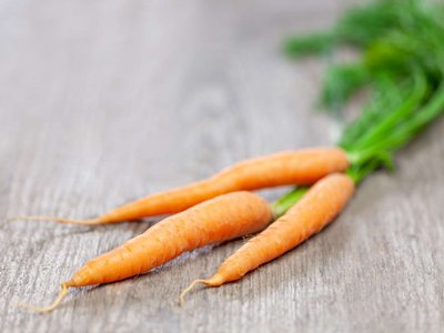 Ein Bund Karotten liegt auf einem Holztisch