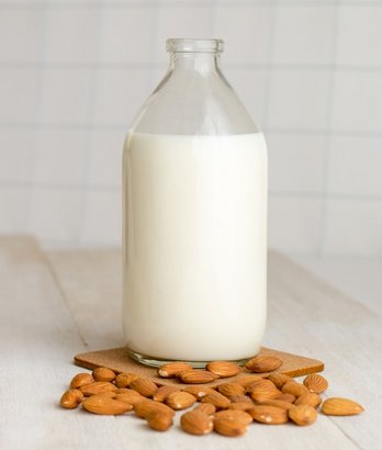 Mandeldrink in Flasche mit Mandeln davor als Milchersatz ©unsplash