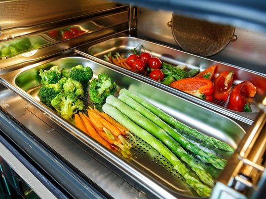 Vegetables on a baking tray prepared in a steam oven