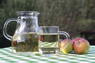 Krug und Glas gefüllt mit Most stehen auf einem tisch mit zwei Äpfeln
