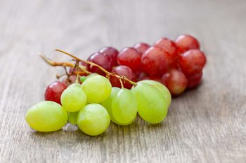 Weiße und rote Weintrauben liegen auf einem Holztisch