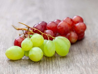 Weiße und rote Weintrauben liegen auf einem Holztisch