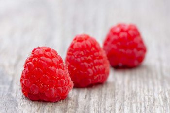 Himbeeren liegen auf einem Holztisch