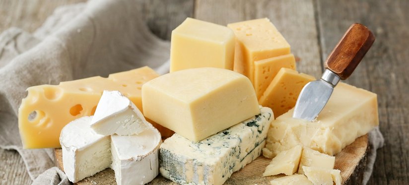 Hartkäse, Weichkäse, Schimmelkäse, Brie und weitere liegen auf Holzbrett angerichtet