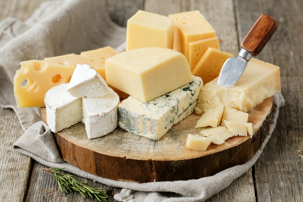 Hartkäse, Weichkäse, Schimmelkäse, Brie und weitere liegen auf Holzbrett angerichtet