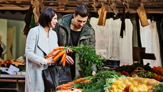 Couple looking at carrots on a market stand