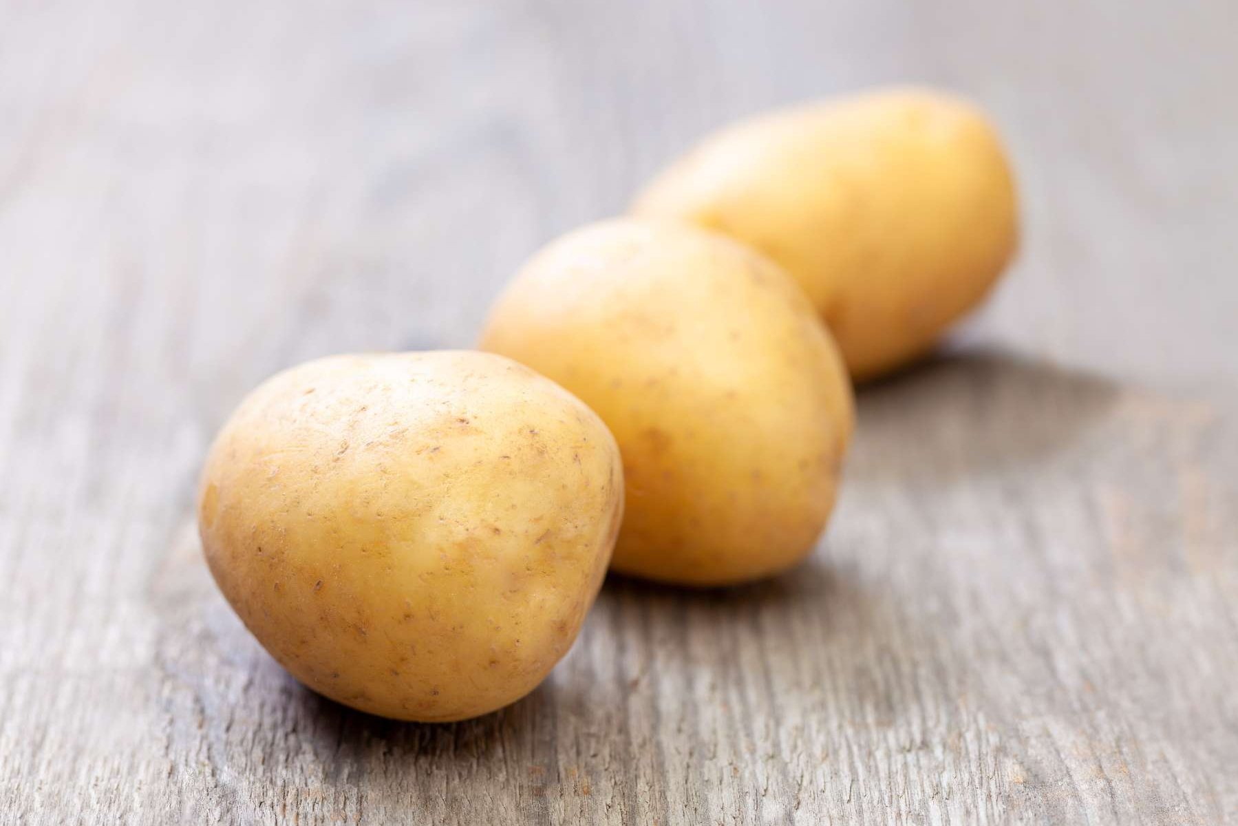 Erdäpfel liegen auf einem Holztisch