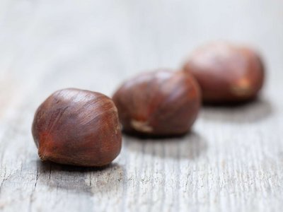 Drei Maroni liegen auf einem Holztisch