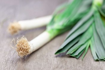 Ein paar Stangen Porree liegen auf einem Holztisch