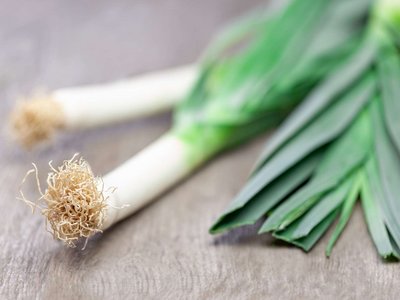 Ein paar Stangen Porree liegen auf einem Holztisch
