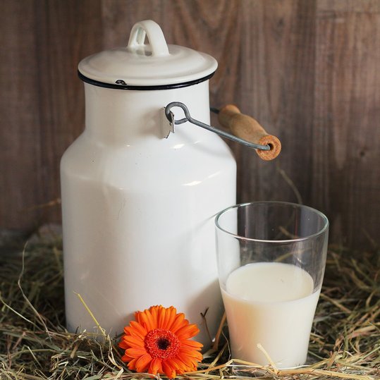 Milch im Glas mit Milchkanne