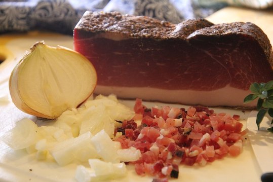 Zwiebel schälen und fein hacken. Speck feinwürfelig schneiden. Den Kürbis schälen und würfelig schneiden.