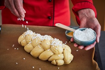 Köchin bestreut Striezel mit Hagelzucker