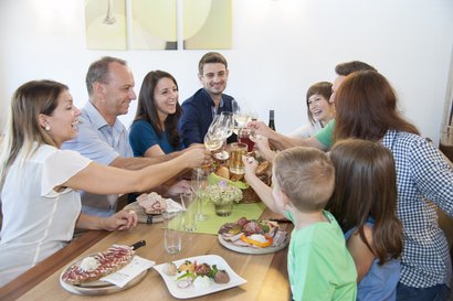 Gruppe Personen sitzt um Tisch und prostet mit Weingläsern bei Top-Heurigen ©Eva Lechner/LK Niederösterreich