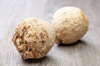 Zwei Sellerieknollen liegen auf einem Holztisch