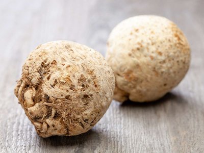 Zwei Sellerieknollen liegen auf einem Holztisch