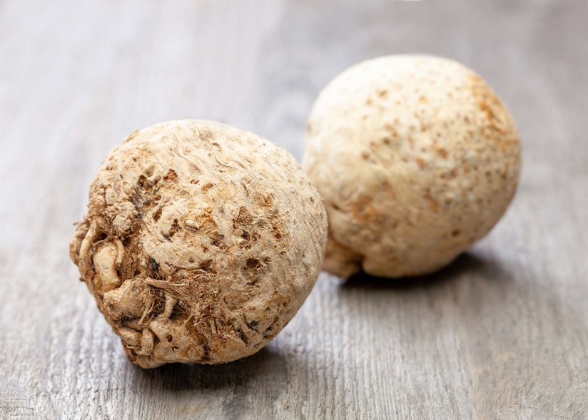 Zwei Sellerieknollen liegen auf einem Holztisch