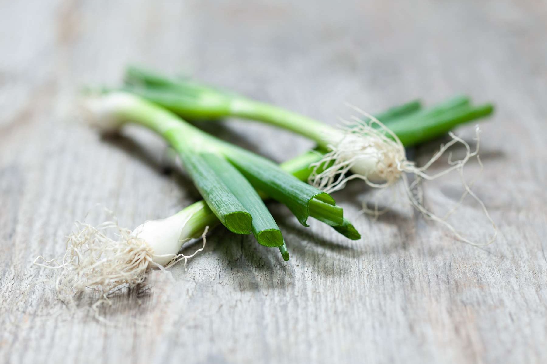 Jungzwiebeln liegen auf einem Holztisch