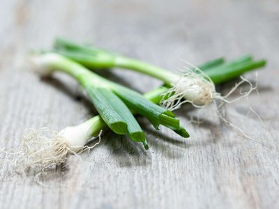 Jungzwiebeln liegen auf einem Holztisch