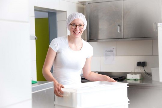 Schafbäuerin und Käserin Melanie Sterkl trägt weiße Produktkiste