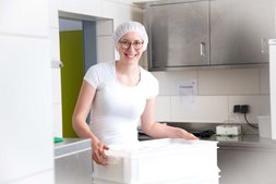 Schafbäuerin und Käserin Melanie Sterkl trägt weiße Produktkiste