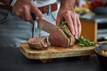 Mann schneidet Fleisch