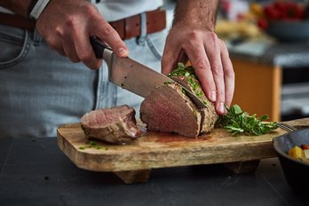 Mann schneidet Fleisch