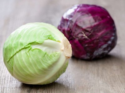 Ein Blaukraut- und ein Weißkrautkopf liegen auf einem Holztisch