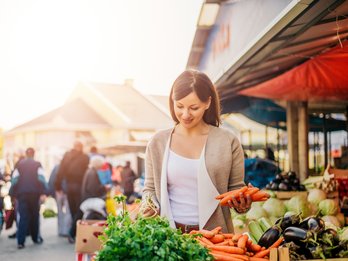 Frau kauft am Markt Obst und Gemüse ein