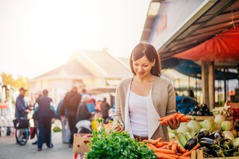 Frau kauft am Markt Obst und Gemüse ein