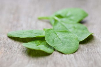 Einige Spinatblätter liegen auf einem Holztisch
