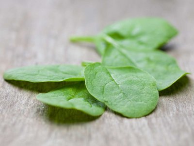 Einige Spinatblätter liegen auf einem Holztisch