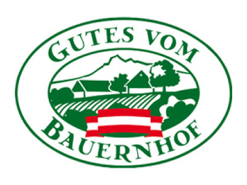 In einer ovalen Form ist mittig eine Landschaft in grün gezeichnet mit rot-weiß-roter Fahne davor. Dieses Bild umgibt der Schritzug "Gutes vom Bauernhof".