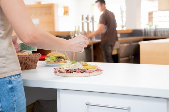 Letzte Handgriffe für die Top-Heurigenjausenplatte. Im Hintergrund wird auch schond er Wein dazu eingeschenkt.