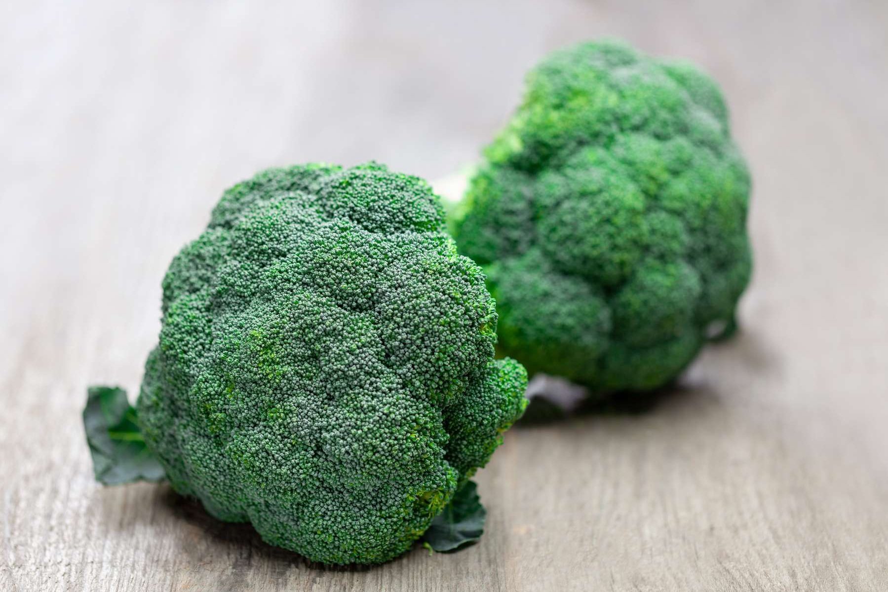 Brokkoliköpfe liegen auf einem Holztisch