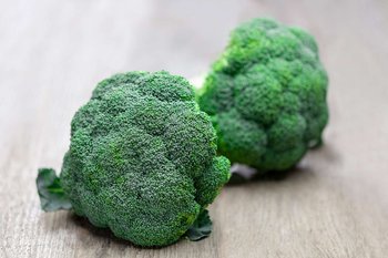 Brokkoliköpfe liegen auf einem Holztisch