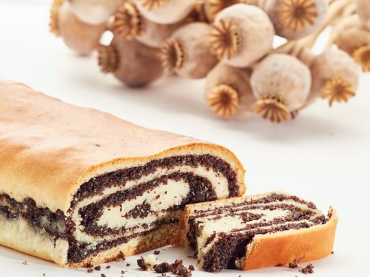 Strudel mit Graumohn angeschnitten dahinter Bund mit Graufmohn-Kapseln