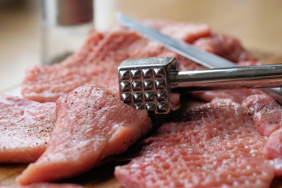Schnitzelfleisch mit Fleischklopfer bearbeiten - das sorgt dafür, dass das Fleisch gleichmäßig zart und saftig ist und es sich beim Braten nicht zusammenzieht.