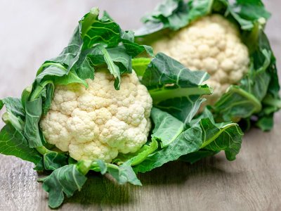 Zwei Karfiolköpfe liegen auf einem Holztisch