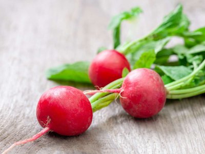 Ein paar Radieschen liegen auf einem Holztisch