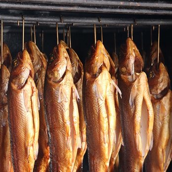Auf mehreren Haken hängen Forellen in der Räucherkammer