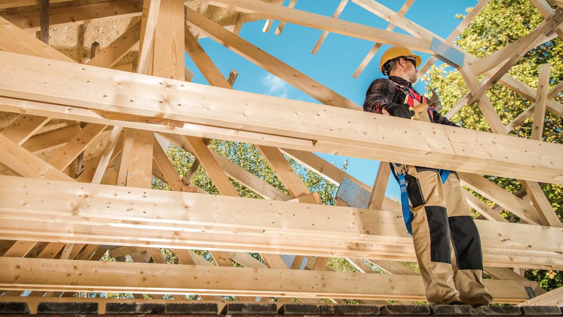 Arbeiter auf Balken beim Bau eines Holzhauses