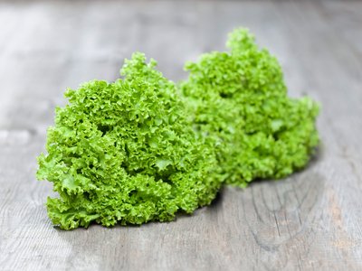 Zwei Salatköpfe liegen auf einem Holztisch