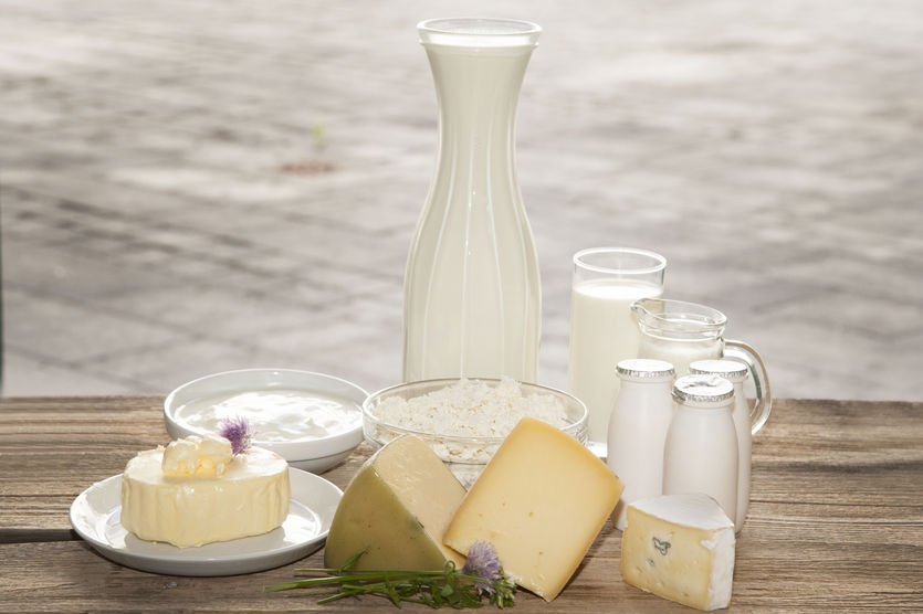 Milch und Milchprodukte wie zum Beispiel Käse, Butter, Topfen und Joghurt stehen auf einem Holztisch