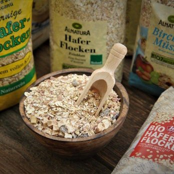 Haferflocken Säcke, die beim Regionalitäts-Check unter die Lupe genommen wurden, mit Haferflocken in einer Schale im Vordergrund