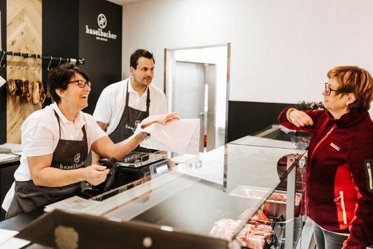 Kunde wird von der Betriebsleiterin Elisabeth Haselbacher an der Kühltheke bedient.