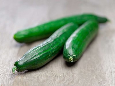 Drei Gurken liegen auf einem Holztisch