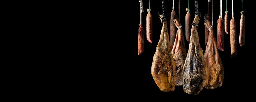 Jamón Serrano y de Bellota, Prosciutto Crudo italiano o Jamón de Parma. Cortar jamón ibérico español. Embutidos y productos de carniceria y comida tradicional.