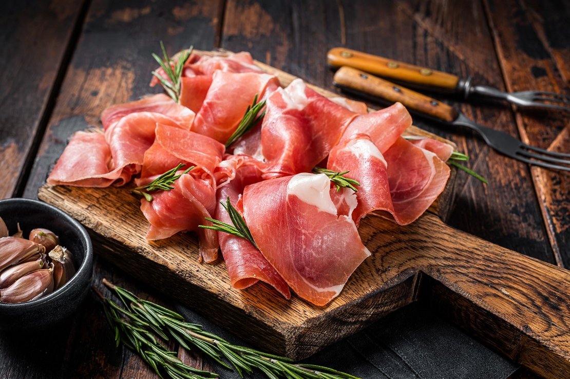 Slices of jamon serrano ham or prosciutto crudo parma on wooden