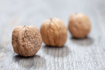 Drei Walnüsse liegen auf einem Holztisch